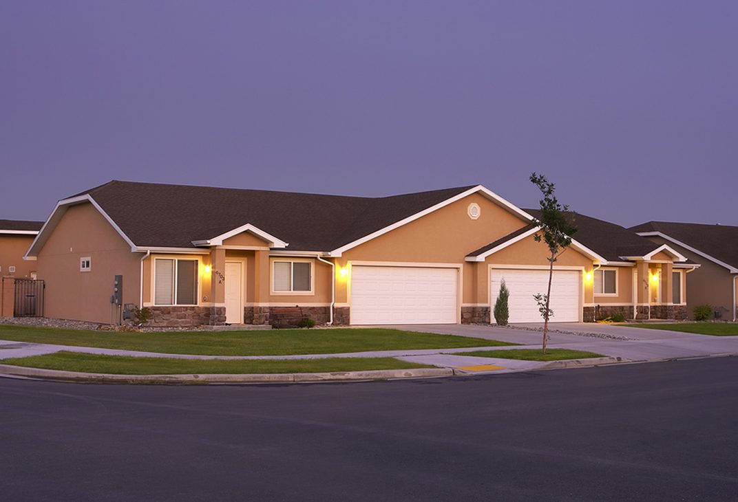 Single-level twin homes with two-car garages at dusk