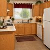 Kitchen with oak cabinets, white appliances, and tile floor