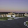Curving residential street lined with twin homes at sunset